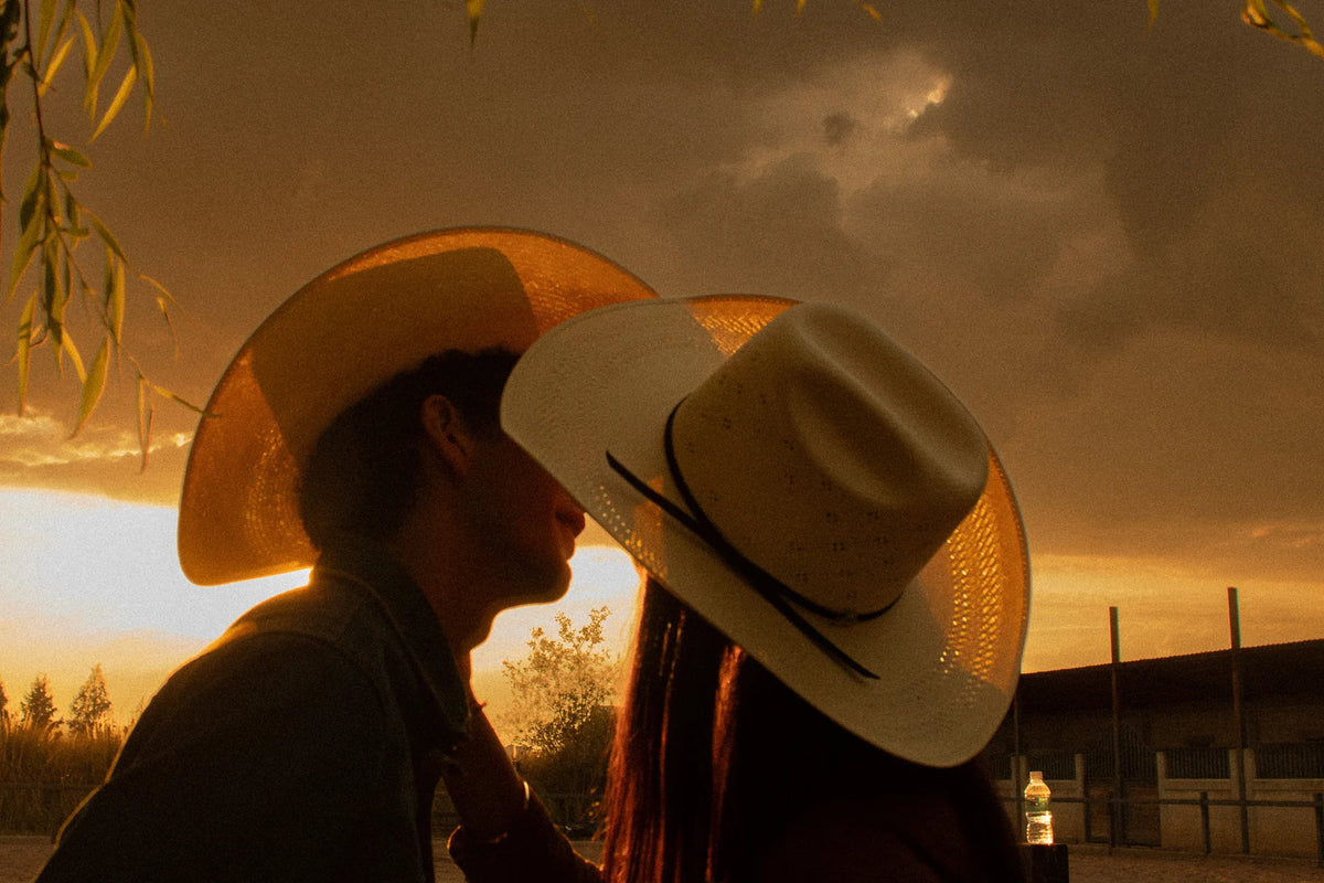 Pareja con sombreros Goose Western al atardecer