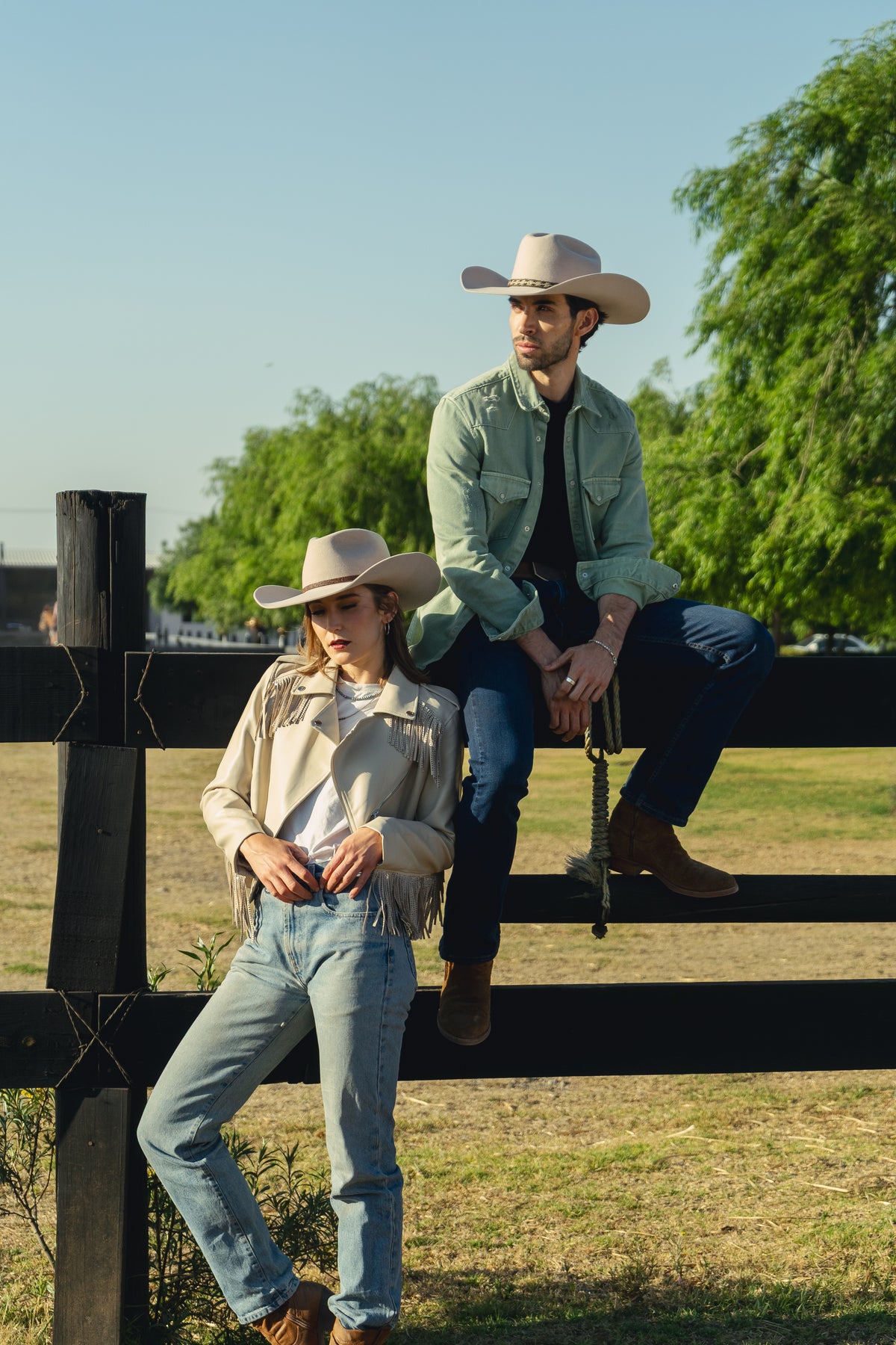 Mujer con texana Beth clara y chamarra con flecos junto a una cerca de rancho