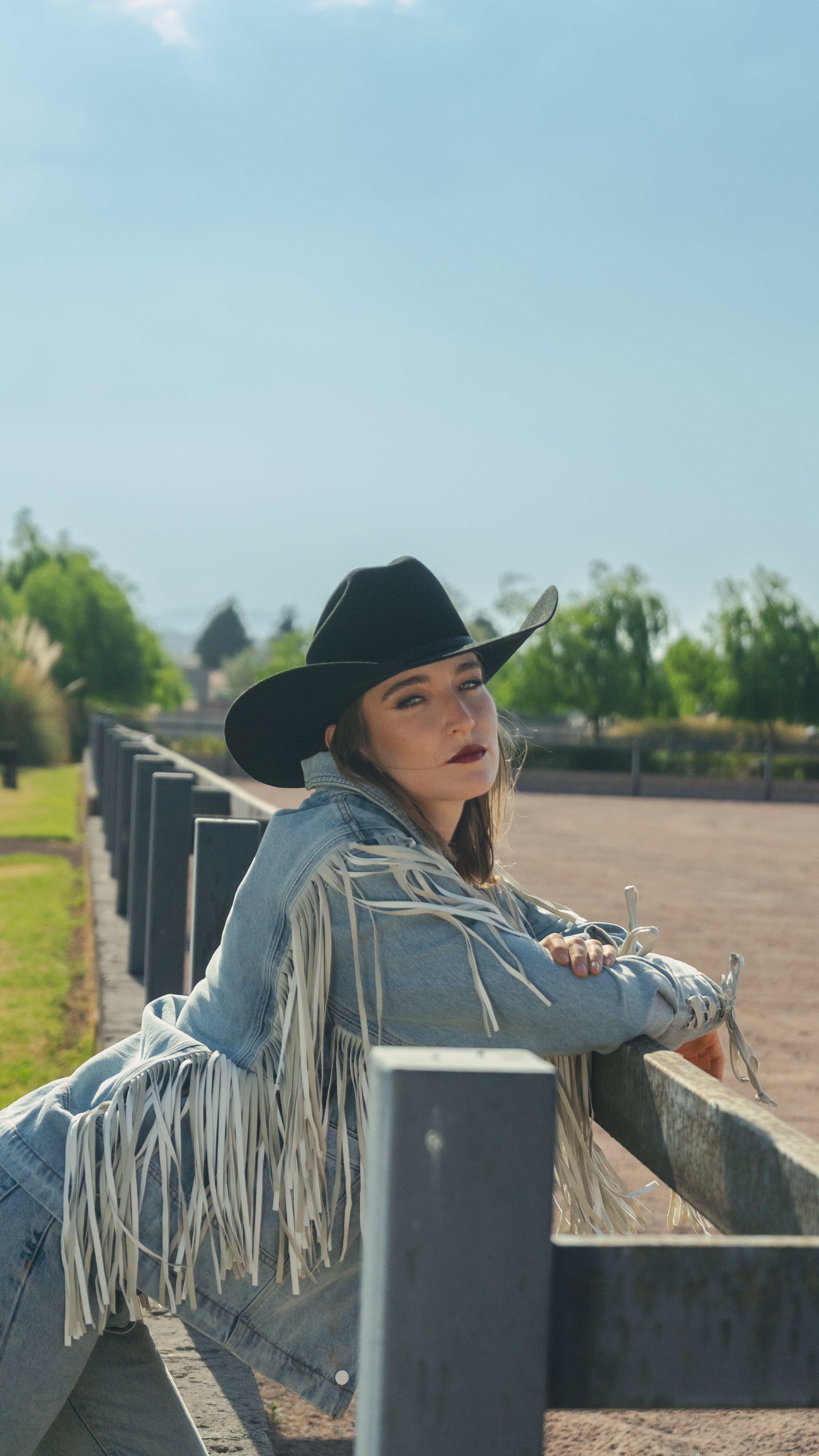 Sombrero John negro en mujer apoyada en la cerca